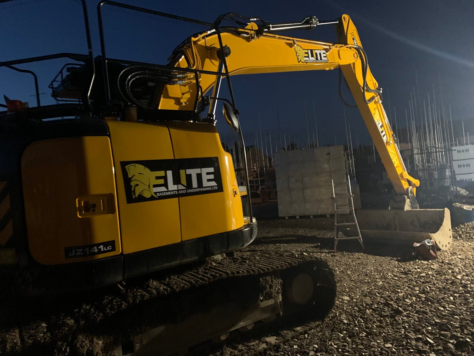 Yellow excavator digger with custom vinyl graphics and professional vehicle branding signage